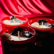 Trzy estetyczne świece zodiakalne Skorpion w czerwonych matowych słoikach, wypełnione kamieniami naturalnymi, idealne na prezent dla zodiakalnego Skorpiona..webp