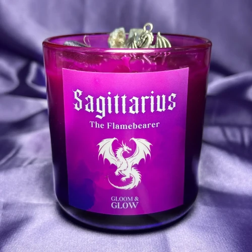 Fioletowa ezoteryczna świeca sojowa Sagittarius marki Gloomandglow z etykietą przedstawiającą smoka na satynowym tle.