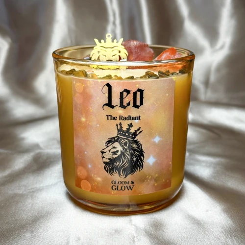Bursztynowa świeca w szkle z serii zodiakalnej Leo (Lew) od gloomandglow. Te ezoteryczne świece sojowe mają ciepłą, pomarańczowo-złotą etykietę z lwem w koronie i stoją na jasnym, satynowym tle.